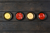 Four sauce bowls with ketchup, mayonnaise, mustard and adjika