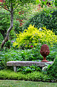 Steinbank mit Terrakotta-Dekoration im grünen Garten