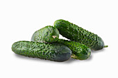 Four small cucumbers against a white background