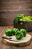 Green pepper with knife on wooden cutting board