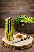 Green asparagus with knife on wooden cutting board