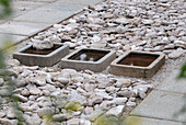 Stone bed with three square concrete water basins in the garden