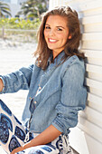 Young woman wearing a denim jacket, a white shirt and blue and white patterned trousers