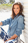 Young woman wearing a denim jacket, a white shirt and blue and white patterned trousers