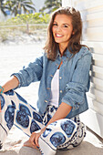 Young woman wearing a denim jacket, a white shirt and blue and white patterned trousers