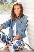 Young woman wearing a denim jacket, a white shirt and blue and white patterned trousers