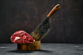 Raw leg of lamb with butcher's cleaver on wooden block