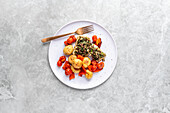 Fish fillet with olive-caper crust, potatoes and baked tomatoes