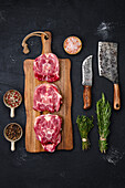 Raw lamb neck steaks with herbs and spices on a chopping board