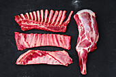 Various pieces of raw lamb on a dark background