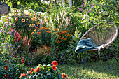 Seat between dahlia (Dahlia), butterfly bush, sunflower (Helenium), lamp cleaner grass in the summer garden