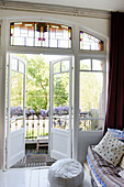 French double doors with leaded glass windows open onto balcony with lilacs