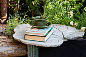 DIY concrete table with books and cup in the garden