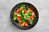 Overhead view of spicy salad with orange, chilli pepper, tomato, cucumber and avocado