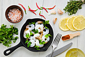 Raw prawns in pans with spices and herbs