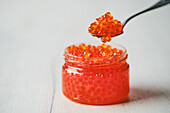 Salmon caviar in a jar and on a spoon