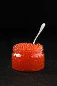 Open jar with red caviar and a spoon in it (photo with full depth of field)