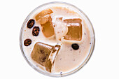 White Russian cocktail with ice cubes and coffee beans