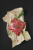 Overhead view of raw beef neck with garlic on wrapping paper