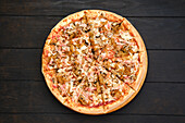 Pizza with bacon, ham, champignon and fried onion, top view