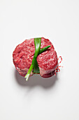Raw beef fillet steak tied with spring onion