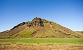 Mountain with slopes covered in green grass in scenic landscape, Iceland