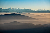 Nebelverhangene Berge im Vordergrund mit dem Himalaya-Gebirge im Hintergrund, Blick von Pangot, Indien