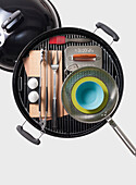 High angle view of barbecue grill and grilling utensils on white background