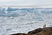 Greenland, west coast, Disko Bay, Ilulissat, hikers on the edge of the icefjord listed as World heritage by UNESCO that is the mouth of the Sermeq Kujalleq Glacier (Jakobshavn Glacier)