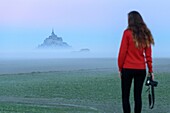 France, Manche, the Mont-Saint-Michel, silhouette of a young photographer at dawn
