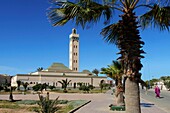 Morocco, Western Sahara, Dakhla, woman wearing traditional Saharawi clothing walking in front of Eddarham Mosque