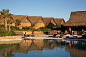 Morocco, Western Sahara, Dakhla, West Point hotel pool with thatched roof bungalows in the background