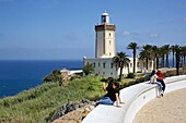 Marokko, Tanger, Region Tetouan, Tanger, Marokkanische Touristen sitzen vor dem Leuchtturm von Kap Spartel mit Blick auf das Mittelmeer