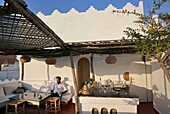 Marokko, Tanger Region Tetouan, Tanger, Hotel Dar Nour, Mann sitzt auf einer Bank auf der Terrasse der Bar des Gästehauses Dar Nour