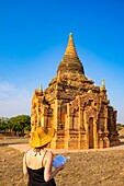 Myanmar (Burma), Region Mandalay, buddhistische archäologische Stätte von Bagan, die von der UNESCO zum Weltkulturerbe erklärt wurde, junge Touristin vor einem Tempel