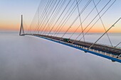 France, between Calvados and Seine Maritime, the Pont de Normandie (Normandy Bridge) emerges from the morning mist of autumn and spans the Seine to connect the towns of Honfleur and Le Havre