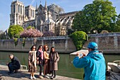 France, Paris, Notre Dame de Paris Cathedral, two days after the fire, April 17, 2019, Asian tourists being photographed in front of the cathedral from the quay of Montebello