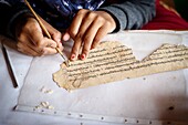 India, state of Jammu and Kashmir, Himalayas, Ladakh, Indus valley, Matho monastery (gompa), in the restoration workshop a woman from the village of Mahto repairs the tears of a prayer book leaflet. She half-open both sides of the thickness and insert a piece of paper