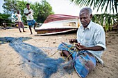 Sri Lanka, Ostprovinz, Passikudah, Fischer flickt sein Netz am Strand von Passikudah