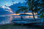 Blick auf einen Einheimischen, der auf einem Boot sitzt und Le Morne von Le Morne Brabant aus bei Sonnenuntergang betrachtet, Distrikt Savanne, Mauritius, Indischer Ozean, Afrika