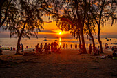 Blick auf Menschen am öffentlichen Strand von Mon Choisy bei Sonnenuntergang, Mauritius, Indischer Ozean, Afrika