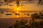 Blick auf Boote am öffentlichen Strand von Mon Choisy bei Sonnenuntergang, Mauritius, Indischer Ozean, Afrika