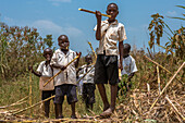 Junge Schuljungen essen Zuckerrohr auf ihrem Heimweg von der Schule, Masindi, Uganda, Ostafrika, Afrika