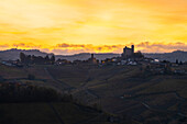 Serralunga d'Alba und sein Schloss mit Weinbergen bei Sonnenaufgang im Gegenlicht im Herbst, Cuneo, Langhe und Roero, Piemont, Italien, Europa