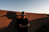 Usa, New Mexico, Santa Fe, Porträt eines Mannes mit Strohhut vor einer Lehmziegelwand
