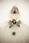 USA, NY, Hammond, Blick von oben auf einen Mann beim Eisfischen auf dem zugefrorenen Black Lake