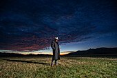 USA, Idaho, Bellevue, Rancher im Mantel steht bei Sonnenaufgang auf einem Feld