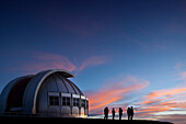 Silhouette von Menschen, die den Sonnenuntergang am Observatorium beobachten