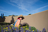 USA, New Mexico, Santa Fe, Frau mit Strohhut und Jeans-Overall bei der Gartenarbeit