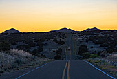 USA, New Mexico, Galisteo, Auto auf Wüstenstraße in der Abenddämmerung